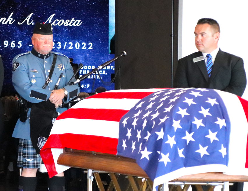 Adams County Sheriff's Deputy and piper Tim Lambert stands with Brighton police Cmdr. Frank Acosta's casket Sept. 29 at Orchard Church.